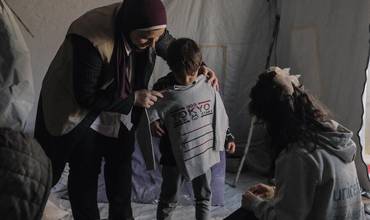 Personal humanitario entregando prendas de abrigo a niños desplazados en Gaza