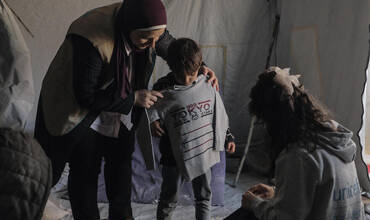 Personal humanitario entregando prendas de abrigo a niños desplazados en Gaza