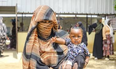 mujer en Sudán con un bebé en brazos