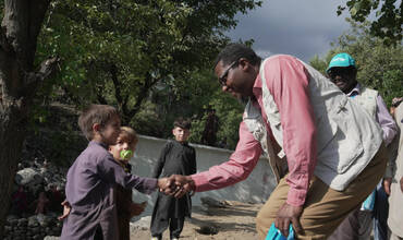 El Dr. Tajudeen Oyewale, representante de UNICEF en Afganistán, da la mano a un niño superviviente de la tragedia
