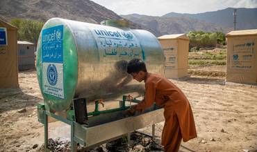 niño afgano bebiendo de uno de los suministros de agua instalados por UNICEF en un campo de refugiados