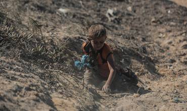 niño en Gaza buscando entre escombros y tierra