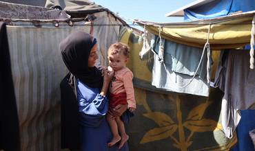 Rania sostiene a su hija Lareen fuera de su tienda improvisada en Al-Mawasi, en la Franja de Gaza.