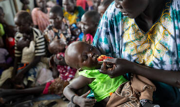un bebé recibe un sobre de alimento terapéutico distribuido por Unicef, de las manos de su madre en Sudán del Sur