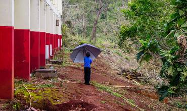 niño sostiene un paraguas en medio del barro
