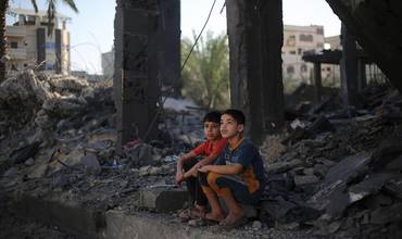 Dos niños sentados entre los escombros de los edificios atacados