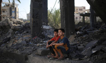Dos niños sentados entre los escombros de los edificios atacados