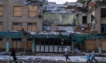 Una familia ucraniana pasa por delante de un edificio destruido por la guerra