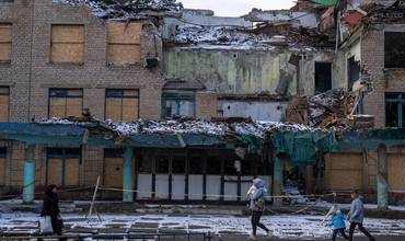 Una familia ucraniana pasa por delante de un edificio destruido por la guerra