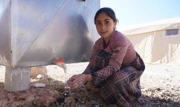 Unha nena nun punto de lavado de mans con auga potable