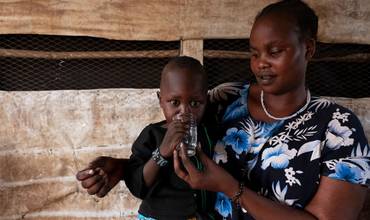 Una madre da agua potable a su niño.