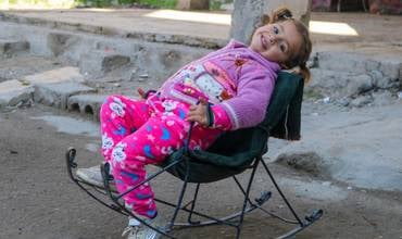 Amneh sentada en una hamaca en el patio de su casa en Siria.