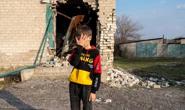 Un niño frente a las ruinas de un edificio destrozado por el conflicto