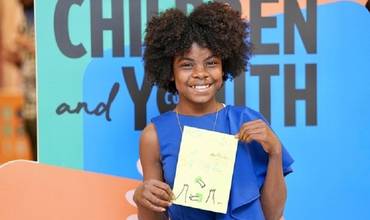 Una niña posa en la COP28 con un dibujo