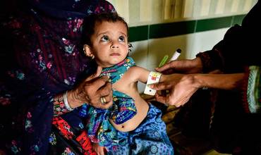Una especialista mide la circunferencia del brazo de un niño pequeño en Pakistán