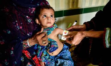 Una especialista mide la circunferencia del brazo de un niño pequeño en Pakistán