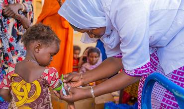 Personal sanitario mide la circunferencia del brazo de un bebé en Malí