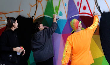 Okuda y adolescentes trabajando en el mural