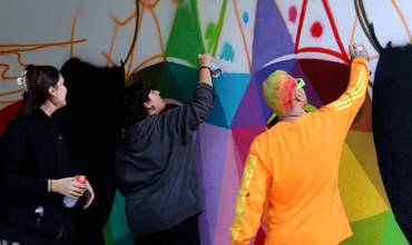 Okuda y adolescentes trabajando en el mural