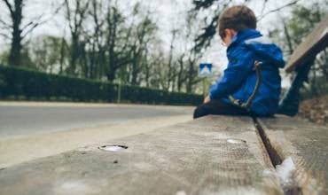 Un niño sentado en un banco. 