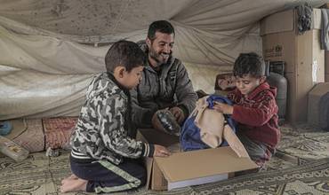 niños abren un paquete con ropa de abrigo para protegerles del frío del invierno