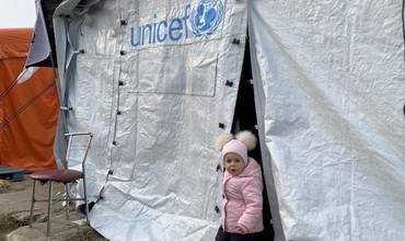 Una niña se asoma de una tienda de campaña de UNICEF en Polonia.