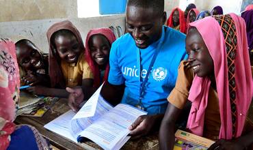 Un miembro del personal de UNICEF lee un libro con unos niños en la escuela municipal de Mongo, en el centro de Chad.
