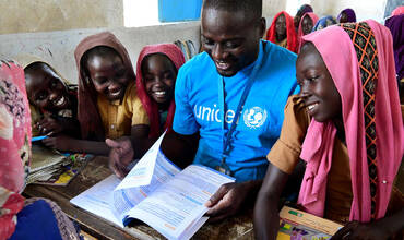 Un miembro del personal de UNICEF lee un libro con unos niños en la escuela municipal de Mongo, en el centro de Chad.