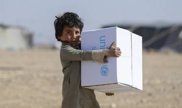 Un niño recoge suministros de invierno distribuidos por UNICEF en Siria.