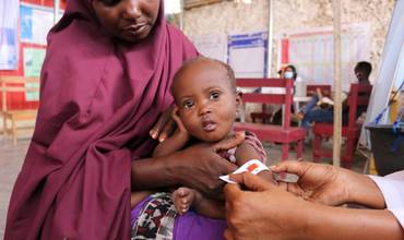 Una trabajadora mide la circunferencia superior del brazo de Sabirin para detectar su estado de nutrición.