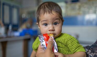 Un niño toma un sobre de alimento terapéutico en Afganistán