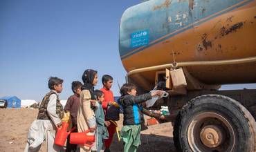 Niños afganos esperan para recoger agua de uno de los camiones cisterna de UNICEF