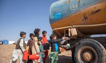 Niños afganos esperan para recoger agua de uno de los camiones cisterna de UNICEF