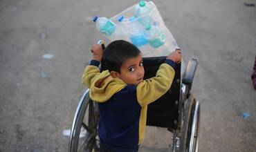 Un niño carga varias botellas de agua vacías en la Franja de Gaza