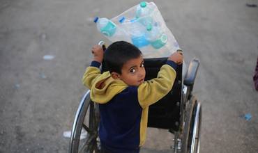 Un niño carga varias botellas de agua vacías en la Franja de Gaza