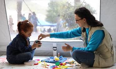 Personal de UNICEF juega con una de las niñas afectadas por el conflicto en uno de los espacios acogedores de UNICEF