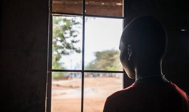 Una adolescente mira a través de una ventana en Uganda