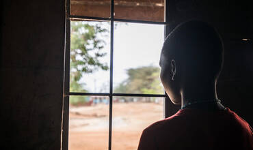 Una adolescente mira a través de una ventana en Uganda