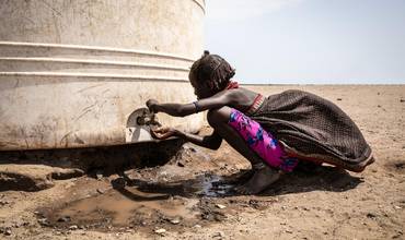 En el distrito de Libemuket, en el sur de Etiopía, afectado por el cambio climático, una niña bebe agua del grifo de un depósito proporcionado por UNICEF en respuesta a la sequía.