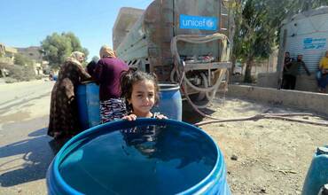 Una niña siria junto a uno de los camiones de UNICEF que transportan agua dentro del país.