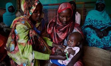Trabajadoras sanitarias de la comunidad miden la circunferencia del brazo de un niño para determinar el grado de desnutrición