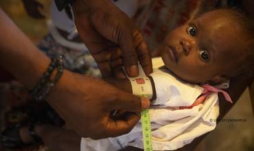 Personal humanitario mide la circunferencia del brazo de un bebé en Haití