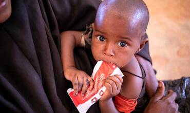 Un niño toma un sobre de alimento terapéutico en un centro de salud de Somalia