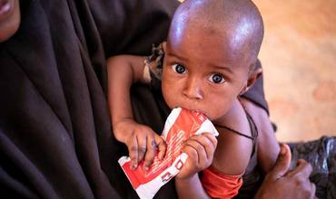 Un niño toma un sobre de alimento terapéutico en un centro de salud de Somalia