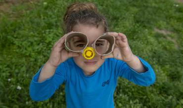 Una niña mira a través de unos anteojos de cartón