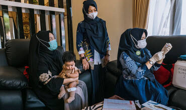 Una enfermera visita a un hogar para vacunar a un niño en Indonesia