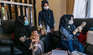 Una enfermera visita a un hogar para vacunar a un niño en Indonesia