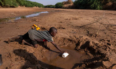 Un niño recoge agua en un río casi seco debido a la sequía en Somalia
