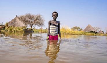 Alekiir Deng Lueth, de 2 años, lava ollas en el agua de la inundación a las afueras de la aldea de Panyagor, en Twic Este, estado de Jonglei, en Sudán del Sur.
