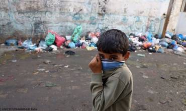 Un niño se tapa la boca para protegerse del polvo de los escombros en la Franja de Gaza